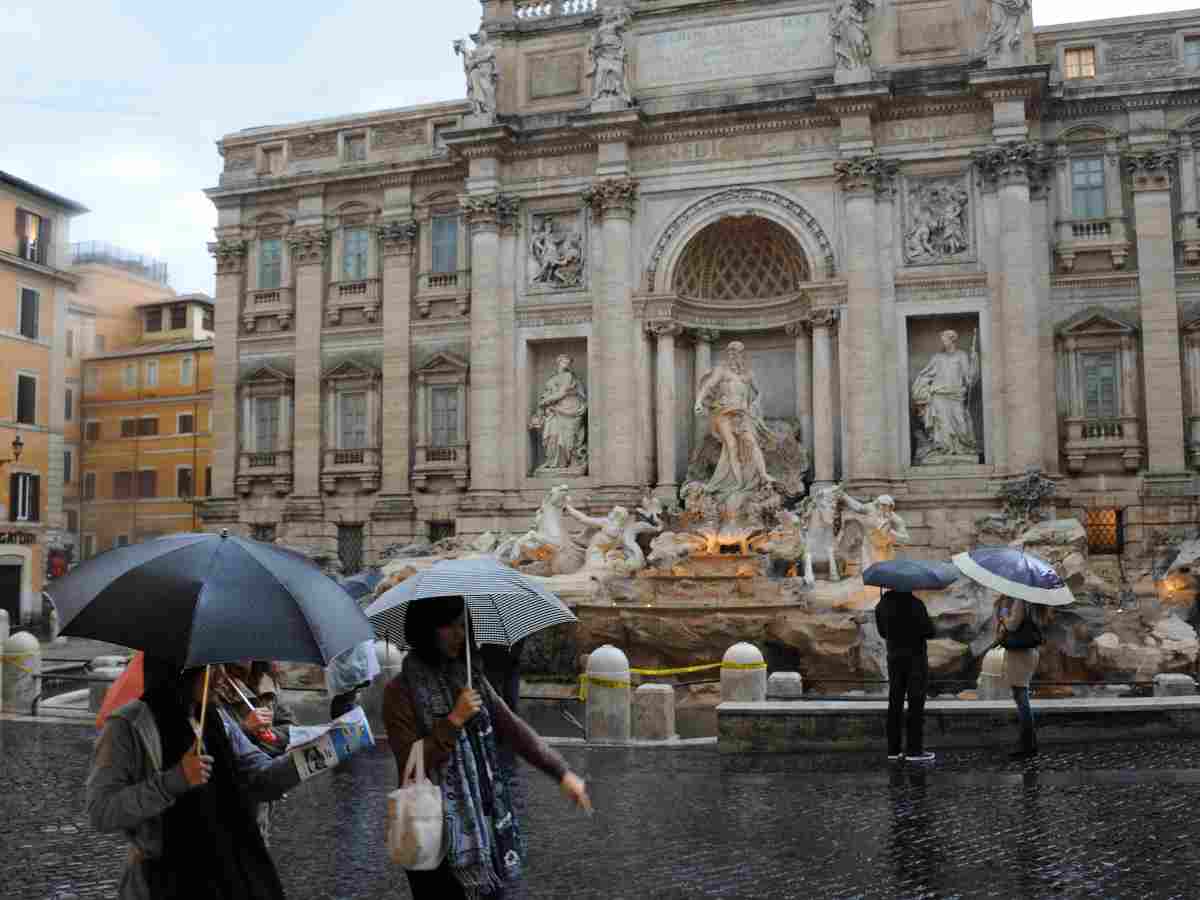 Gente che passeggia sotto la piogga nei pressi della Fontana di Trevi 