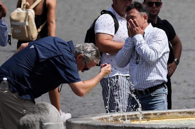 due uomini si rinfrescano con l'acqua di una fontana per il caldo