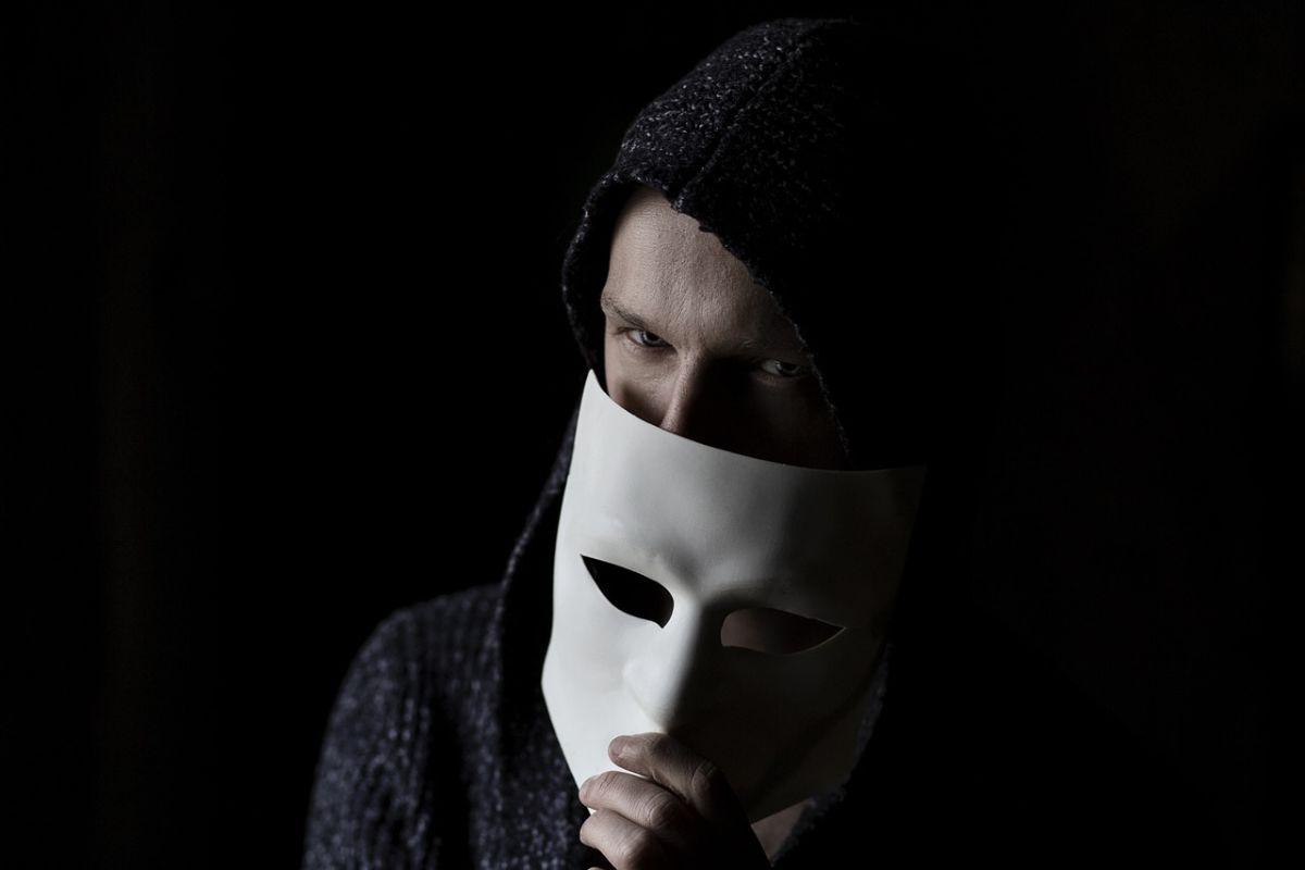 un uomo incappucciato con una maschera da hacker